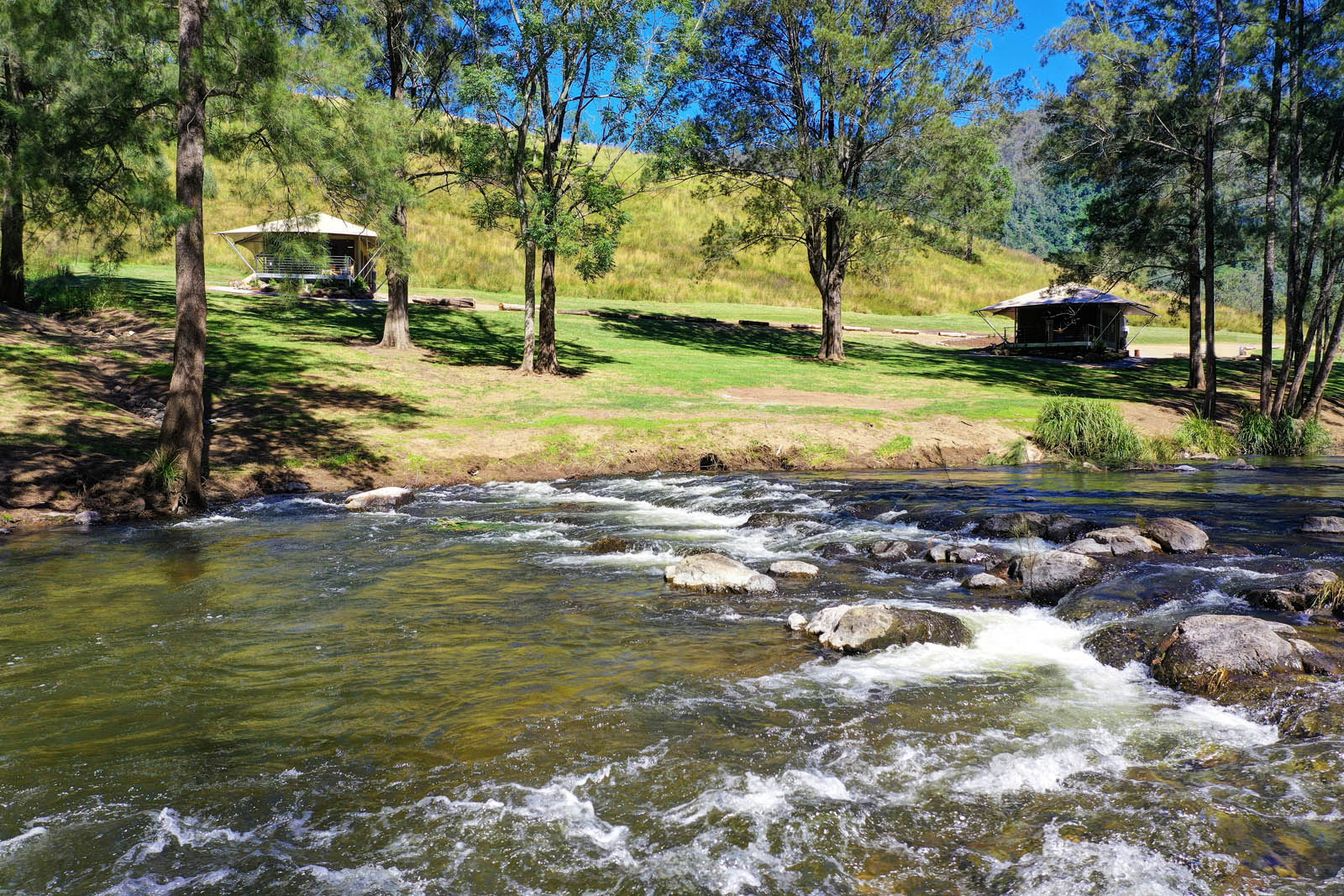Glamping tents on the hillside across the Manning River